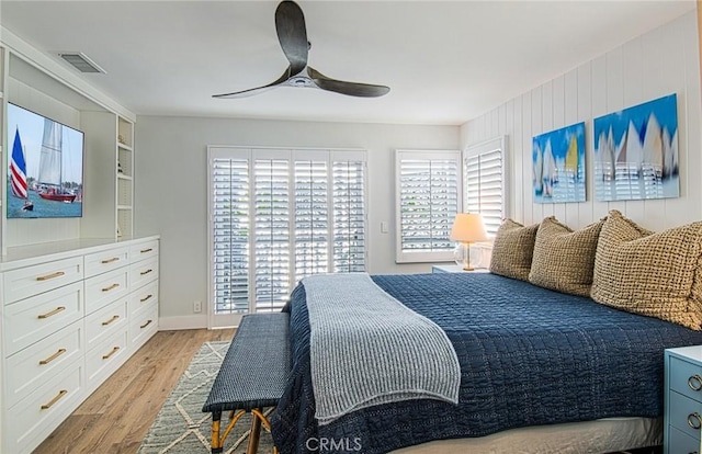 bedroom featuring light hardwood / wood-style floors, multiple windows, wooden walls, and ceiling fan