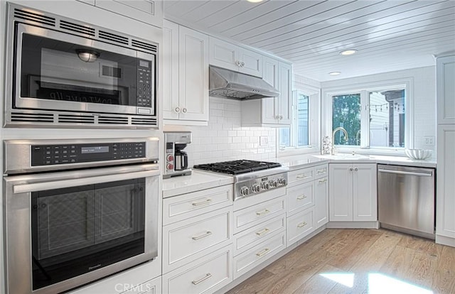 kitchen with backsplash, white cabinets, sink, light wood-type flooring, and stainless steel appliances