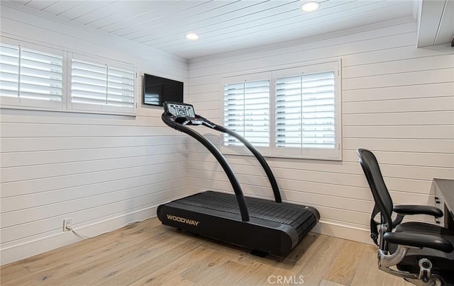 workout area with wood walls and light wood-type flooring