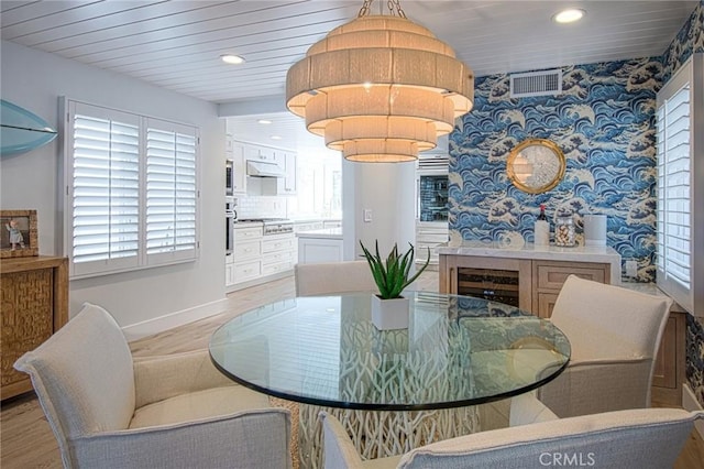 dining area featuring light hardwood / wood-style floors, wood ceiling, and beverage cooler