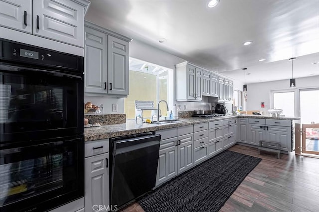 kitchen featuring kitchen peninsula, dark hardwood / wood-style flooring, sink, black appliances, and pendant lighting