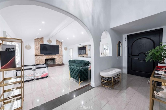 entryway with tile patterned floors, lofted ceiling with beams, and a fireplace