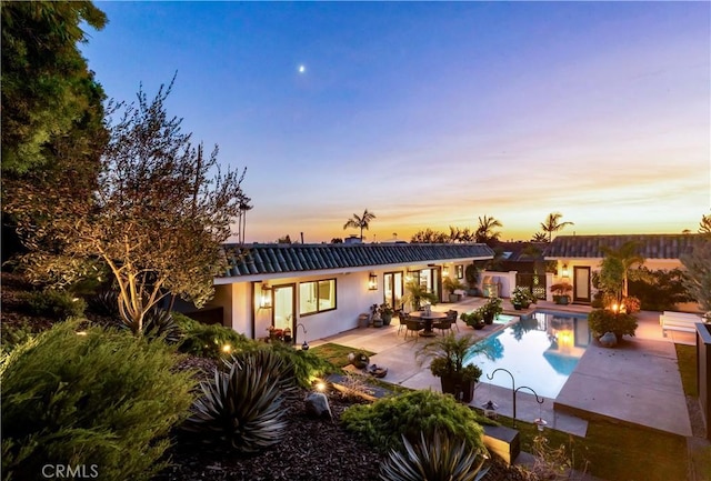 back house at dusk featuring a patio area