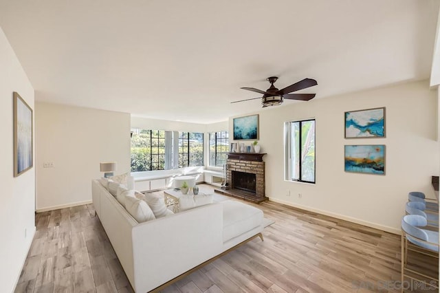 living room featuring ceiling fan, a fireplace, and light hardwood / wood-style floors