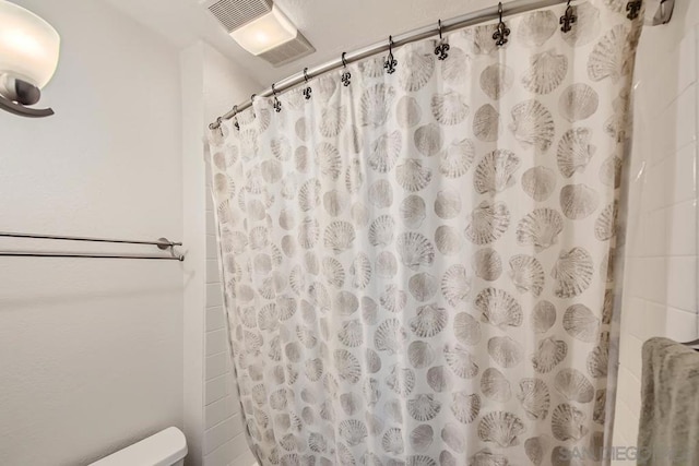 bathroom featuring a shower with shower curtain and toilet