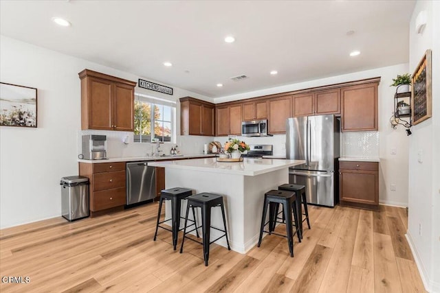 kitchen with a center island, light hardwood / wood-style floors, stainless steel appliances, and a breakfast bar area