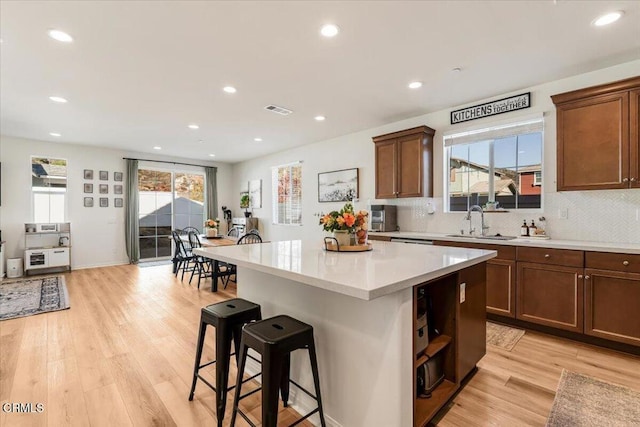 kitchen with decorative backsplash, a center island, light hardwood / wood-style floors, and sink