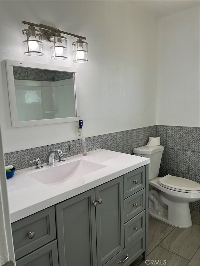 bathroom featuring tile walls, vanity, and toilet