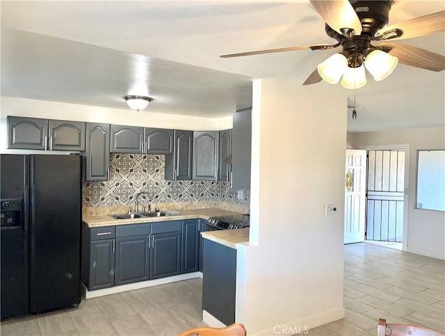 kitchen with sink, blue cabinetry, range with electric stovetop, black fridge, and decorative backsplash