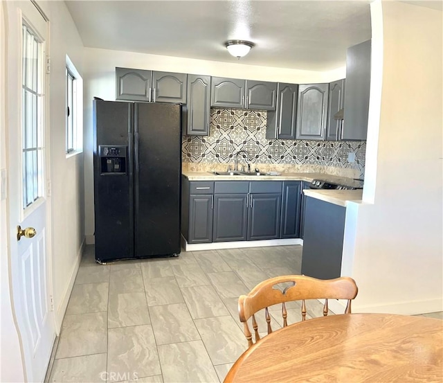 kitchen featuring decorative backsplash, sink, and black refrigerator with ice dispenser