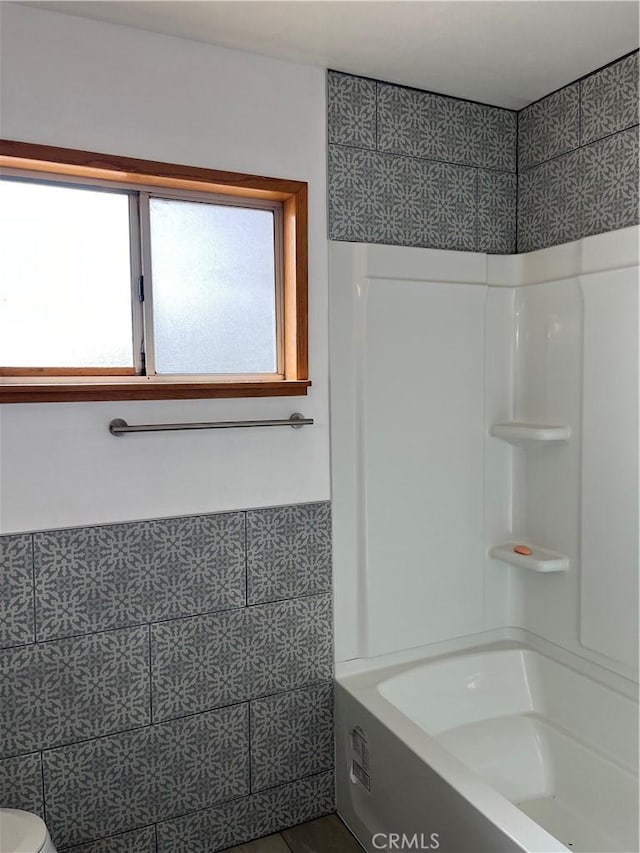 bathroom with washtub / shower combination and tile walls