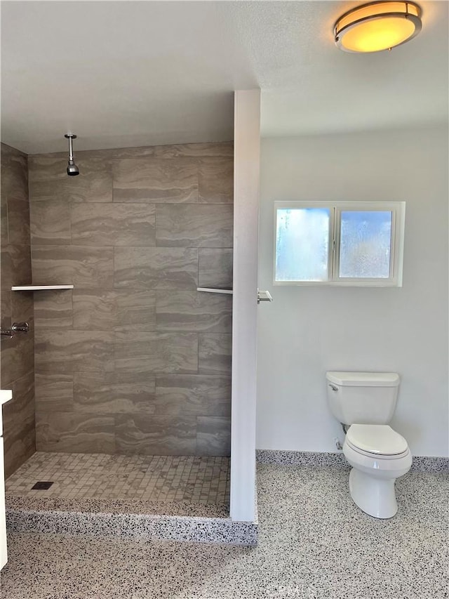 bathroom featuring tiled shower and toilet