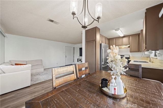 dining area with a textured ceiling, sink, a chandelier, and dark hardwood / wood-style floors