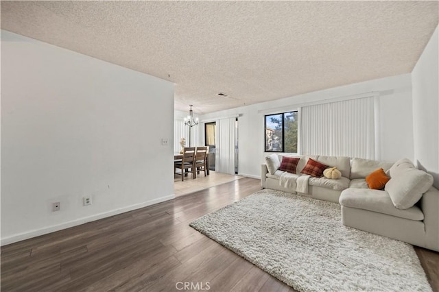 living room featuring dark hardwood / wood-style flooring, a textured ceiling, and an inviting chandelier