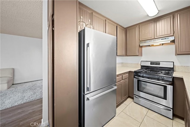 kitchen featuring stainless steel appliances, a textured ceiling, and light wood-type flooring