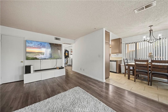 living room with a textured ceiling, hardwood / wood-style flooring, and an inviting chandelier