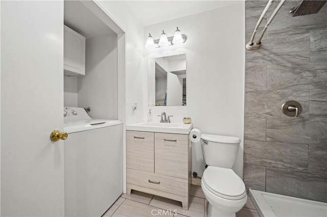 bathroom featuring washer / dryer, tile patterned floors, tiled shower, toilet, and vanity