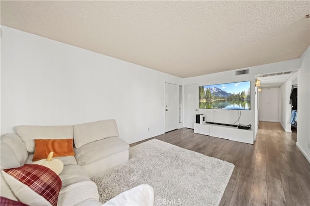 living room with a textured ceiling and dark hardwood / wood-style floors