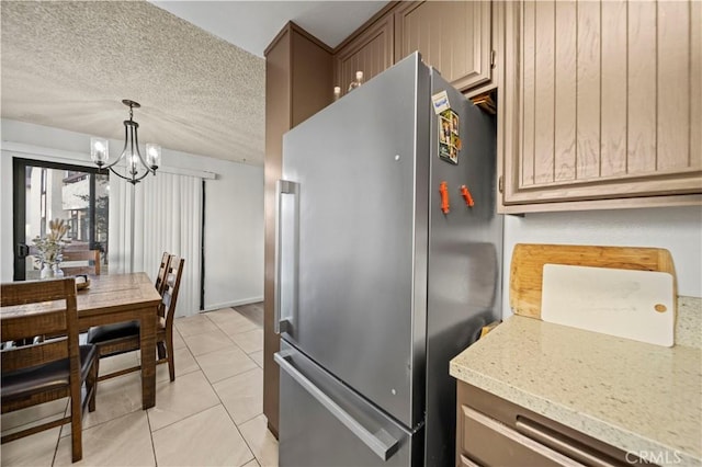 kitchen featuring a textured ceiling, pendant lighting, a notable chandelier, stainless steel refrigerator, and light tile patterned flooring