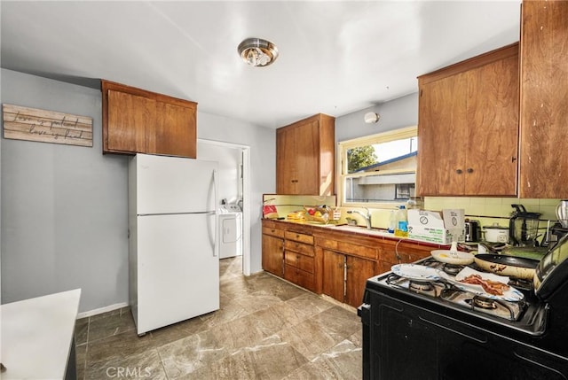 kitchen with decorative backsplash, white appliances, washing machine and dryer, and sink