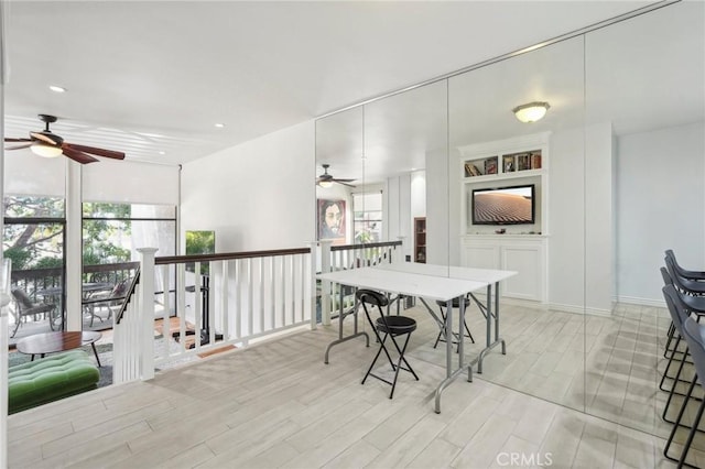 dining room with built in shelves, ceiling fan, and light hardwood / wood-style flooring