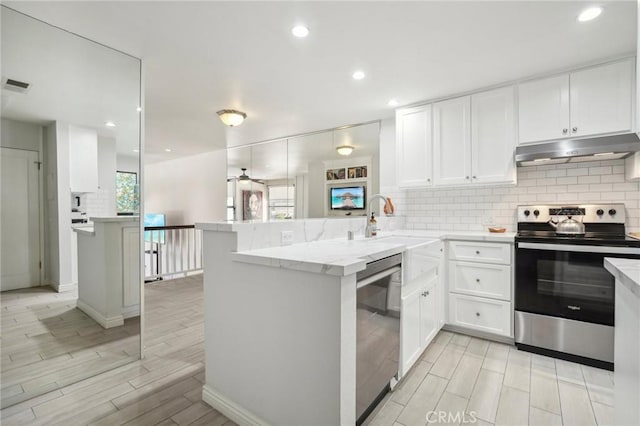 kitchen with kitchen peninsula, appliances with stainless steel finishes, and white cabinets