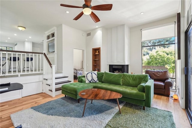 living room with ceiling fan, a fireplace, and light hardwood / wood-style floors