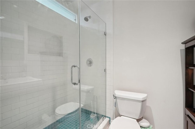 bathroom featuring toilet and a shower with shower door