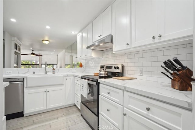 kitchen with white cabinets, sink, ceiling fan, light stone countertops, and stainless steel appliances