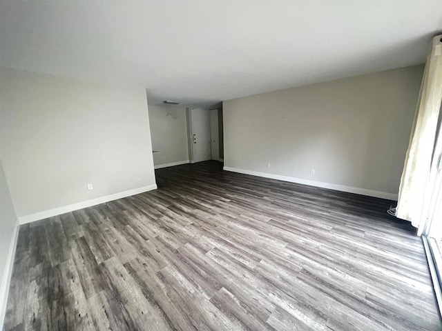 empty room featuring baseboard heating and hardwood / wood-style floors