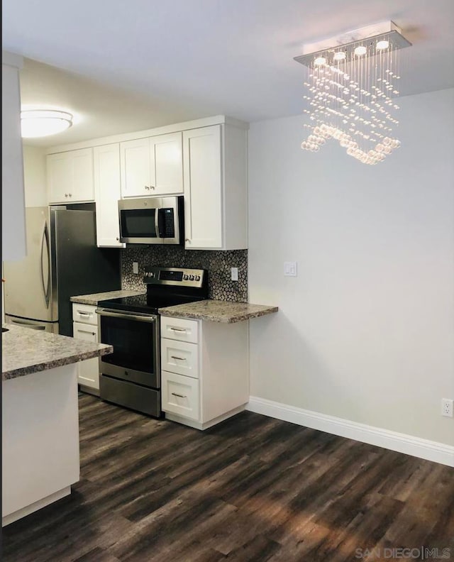 kitchen featuring an inviting chandelier, appliances with stainless steel finishes, dark hardwood / wood-style flooring, white cabinets, and light stone counters