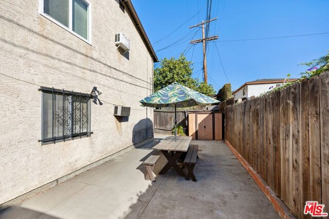 view of patio / terrace with a wall mounted air conditioner and a storage shed