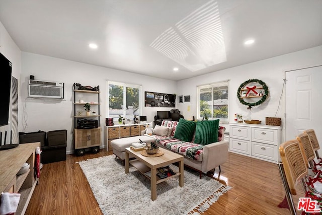 living room featuring hardwood / wood-style floors, a wall unit AC, and a wealth of natural light