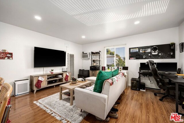 living room featuring hardwood / wood-style floors and an AC wall unit