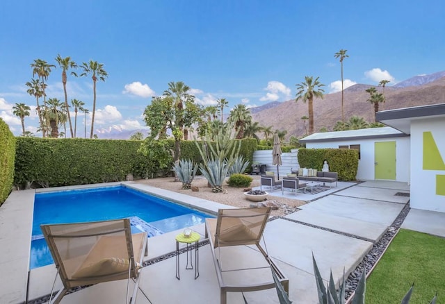 view of pool with outdoor lounge area, a mountain view, and a patio area