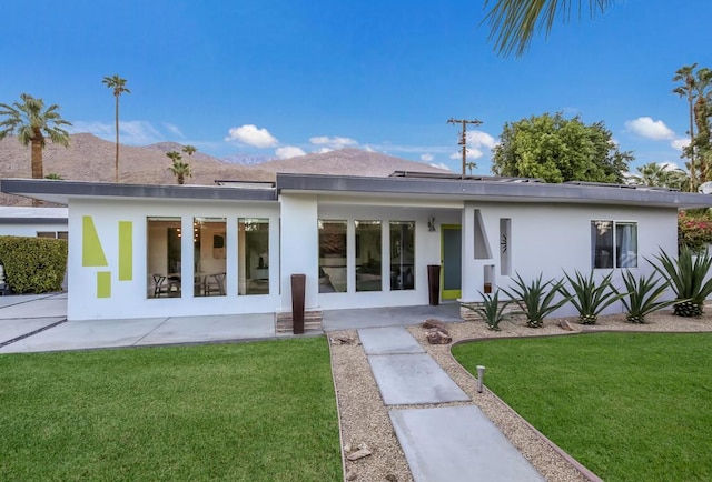 rear view of property with a lawn and a mountain view