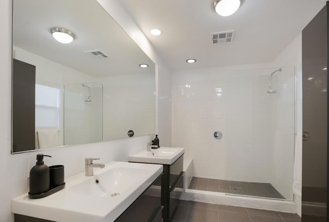 bathroom featuring a tile shower, vanity, and tile patterned floors