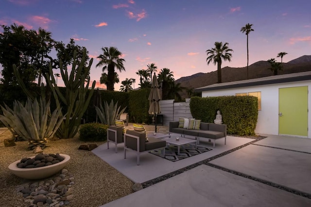 patio terrace at dusk featuring a mountain view and an outdoor hangout area