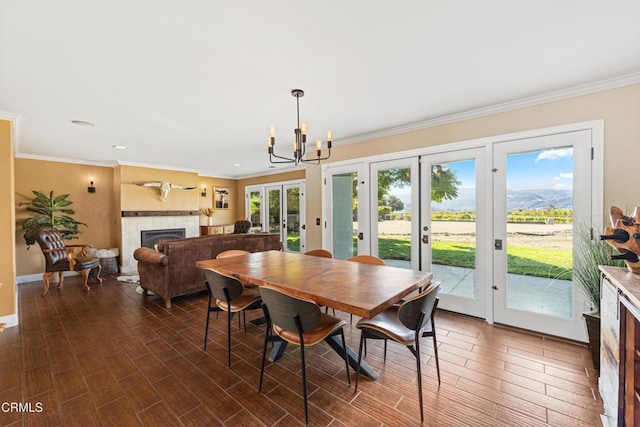 dining room featuring ornamental molding, a wealth of natural light, a tile fireplace, and french doors