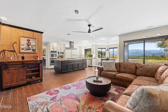 living room featuring a mountain view, crown molding, and ceiling fan