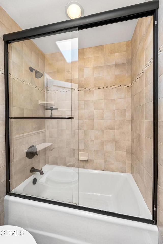 bathroom with toilet and shower / bath combination with glass door