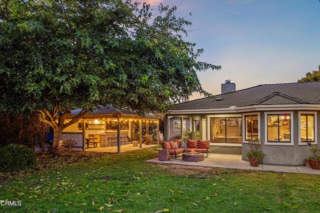 back house at dusk with an outdoor living space, a lawn, and a patio