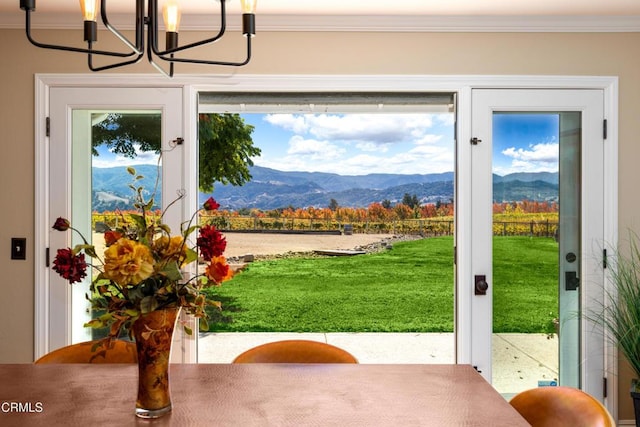 entryway with crown molding, a mountain view, and a notable chandelier