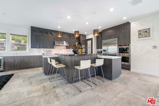 kitchen with appliances with stainless steel finishes, decorative light fixtures, extractor fan, and a spacious island