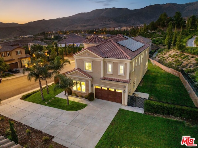 mediterranean / spanish-style home featuring a mountain view, a garage, solar panels, and a yard