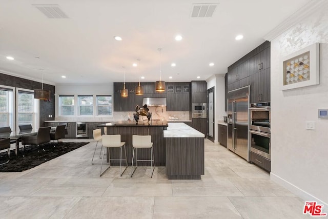 kitchen featuring a center island, decorative light fixtures, built in appliances, and beverage cooler