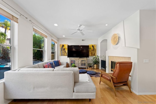 living room with ceiling fan, light hardwood / wood-style flooring, and a tile fireplace