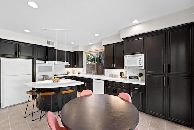 kitchen with white appliances, a center island, decorative backsplash, sink, and light tile patterned floors