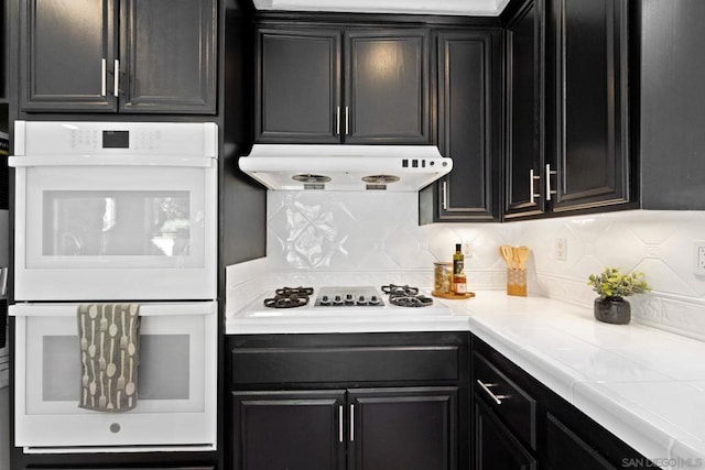 kitchen with decorative backsplash, white appliances, and ventilation hood