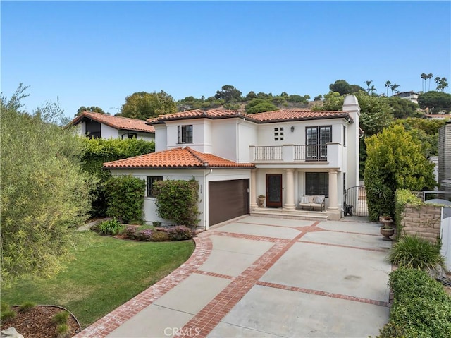 mediterranean / spanish-style home with a balcony, a garage, and a front lawn